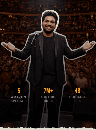 Zakir Khan on stage, arms open, before a packed hall